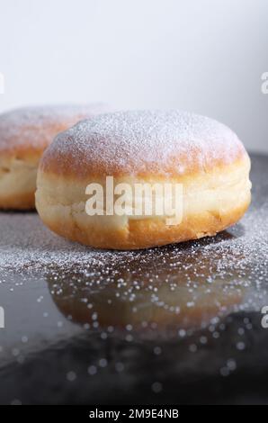 Beignets allemands berliner avec sucre en poudre sur fond noir gros plan Banque D'Images