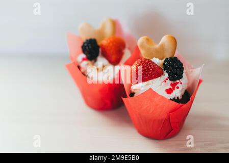 Cupcakes aux fraises fraîches et aux baies de mûres, et biscuits crème et doux avec un accent en premier plan Banque D'Images