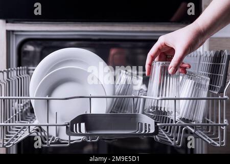 Une femme a fait la vaisselle à la main, a vidé ou a déchargé le lave-vaisselle avec les ustensiles.Appareils de cuisine, vue sur le style de vie.Une femme met une plaque au lave-vaisselle ou en prend.Femme au foyer fait son ménage Banque D'Images