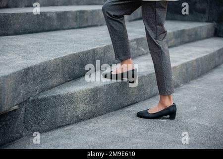 Gros plan les jambes d'une femme d'affaires se précipitent sur l'escalier Banque D'Images