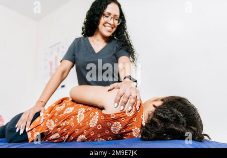 Physiothérapeute réhabilitant l'épaule à la patiente couchée sur le côté. Traitement de l'épaule et du dos et concept de réadaptation, femme faisant l'épaule Banque D'Images