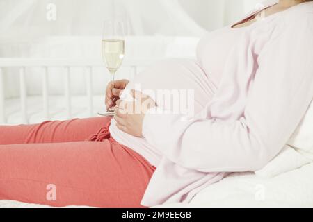 Femme enceinte avec une coupe de champagne sur la bosse de son bébé Banque D'Images