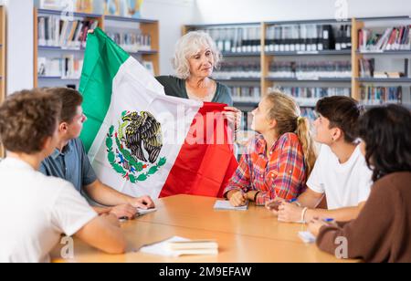 L'enseignante mature montre aux jeunes enfants le drapeau national du Mexique Banque D'Images