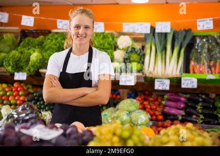 Jolie jeune vendeuse qui se pose à l'épicerie Banque D'Images