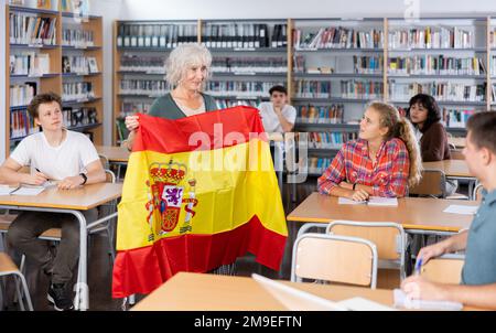 L'enseignante mature montre les jeunes enfants le drapeau national de l'Espagne Banque D'Images