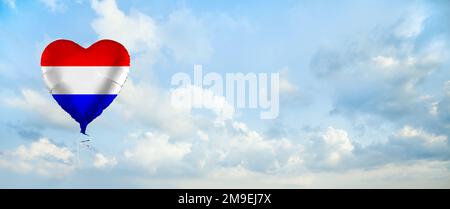 Drapeau des pays-Bas sur une montgolfière en forme de cœur sur fond de nuages de ciel. Éducation, charité, émigration, voyages et apprentissage. Concept de langue néerlandaise Banque D'Images