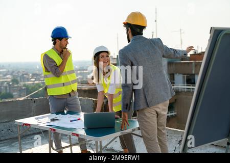 Équipe diversifiée de spécialistes avec ordinateur sur le chantier de construction. Projet de construction avec des ingénieurs Banque D'Images