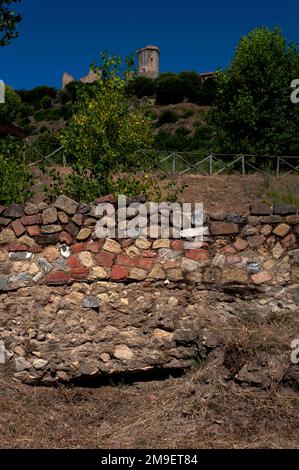 Une tour médiévale s'élève au milieu des ruines du château et des vestiges d'un temple grec sur l'acropole du port gréco-romain de Velia, par Marina di Ascea sur la côte de la mer Tyrrhénienne dans la région du Cilento de Campanie, dans le sud de l'Italie. Un ancien mur en ruines se dresse au premier plan avec ses fondations exposées. Banque D'Images