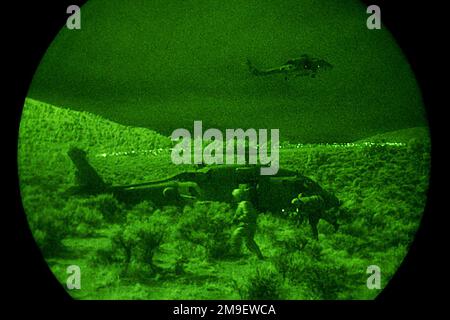 Profil de droite tir moyen la nuit à travers un système Starlight comme US Navy HH-60 Seahawk hélicoptères affectés à l'hélicoptère anti-sous-marin Escadron-aile Pacifique, ramasser un ramasse. Desert Rescue est la première recherche et sauvetage (SAR), formation menée dans les gammes de Fallon Naval Air Station, Nevada. Cette mission est un soutien indirect de l'exercice Desert Rescue VIII Sujet opération/série: BASE DE SAUVETAGE DANS LE DÉSERT: Station navale aérienne, Fallon État: Nevada (NV) pays: États-Unis d'Amérique (USA) Banque D'Images