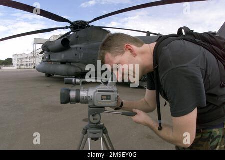 Vue du côté gauche vue de face moyenne vue longue tandis que le sergent technique de la Force aérienne américaine John Trautt, un vidéographe du 786th e Escadron de communications de la base aérienne de Ramstein, en Allemagne, tire un C-130 (non illustré) chargé de fournitures humanitaires alors qu'il part dans une autre mission pour livrer les fournitures nécessaires à Beira, Mozambique le 17 mars 2000. Lui et son équipe sont déployés ici pour soutenir l'opération Atlas Response, une opération d'aide humanitaire destinée à aider la population du Mozambique, après de graves inondations (inondations et victimes non montrées) ont déplacé plus d'un million de personnes de leurs foyers. Opération du sujet/ Banque D'Images