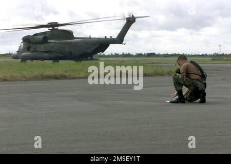 Vue de profil du côté gauche, en tant que capitaine de la US Air Force Jeff Burrell, officier en charge des plans logistiques et du mouvement du fret, du quartier général de la United States Air Force Europe, branche logistique, base aérienne de Ramstein, Allemagne, Vérifie l'heure à laquelle un autre C-130 chargé de fournitures humanitaires arrivera à l'aéroport international de Maputo, au Mozambique, en Afrique, tandis qu'un hélicoptère-taxi MH-53M Pave Low chargé à destination de la piste le 17 mars 2000. Lui et son équipe sont déployés ici pour soutenir l'opération Atlas Response, une opération d'aide humanitaire destinée à aider le peuple mozambicain, après une grave inondation Banque D'Images
