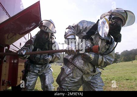Tout droit sur un gros plan moyen tandis que les pompiers de l'US Air Force réagissent à un scénario d'exercice d'incendie dans les logements de base. Le CHEF des pompiers de Vandenberg, le CHEF Benning (non représenté), a aidé l'équipe de l'inspecteur général à installer une machine à fumée, des lumières et des « victimes » au 606 Juniper Street. Les pompiers ont été inspectés selon les procédures au cours de l'inspection de préparation opérationnelle (ORI) de l'escadre spatiale de 30th. Deux pompiers Air Force, en combinaisons de protection ignifuges, tirent un tuyau d'incendie du côté d'un moteur d'incendie partiellement vu. Tout droit sur un gros plan moyen tandis que les pompiers de l'US Air Force réagissent à un scénario d'exercice d'incendie dans les logements de base. V Banque D'Images