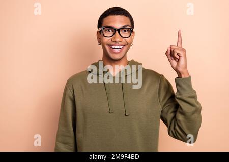Photo de jeune étudiant d'université excité homme porter kaki cavalier point finger vers le haut génie idée eureka résoudre des problèmes isolés sur fond beige couleur Banque D'Images