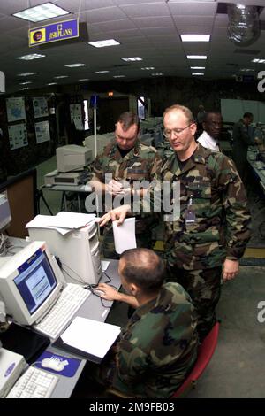 À l'appui de l'expérience 2000 des forces expéditionnaires interarmées (JEFX 2000), le capitaine de la Force aérienne des États-Unis Bob Maxwell (au milieu), 32nd Escadron du renseignement aérien, base aérienne de Ramstein, Allemagne, dicte des données de ciblage avec le CPT Rex Miller (assis), USAF, 497th Groupe des opérations d'information/ Division de ciblage, base aérienne de Bolling, Washington, D.C., tandis que le lieutenant-colonel Lewis Hill (à droite), USAF, CHEF du ciblage, quartier général du Commandement du combat aérien, Langley AFB, Virginie, prend des notes, aire d'exercice permanente, Hurlburt Field, Floride. JEFX 2000 démontrera la capacité de déploiement et d'utilisation de l'USAF Banque D'Images