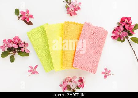 Nouveau chiffon en microfibre plié pour le nettoyage sur fond blanc avec fleurs printanières. Nettoyage des microserviettes en tissu pour épousseter et polir. Concept de service de nettoyage domestique. Vue de dessus Banque D'Images