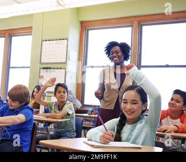 L'éducation, l'enseignant et les enfants lèvent leurs mains pour poser ou répondre à une question académique pour l'apprentissage. Diversité, école et école primaire Banque D'Images