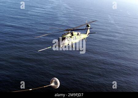 Vue aérienne du côté gauche d'un hélicoptère Pavehawk HH-60G de l'aile de sauvetage 129th, de la Garde nationale aérienne de Californie, du champ fédéral de Moffett, en approchant du tuyau de ravitaillement et de la glissière d'un avion au-dessus de l'océan Pacifique. Pays : Océan Pacifique (POC) Banque D'Images