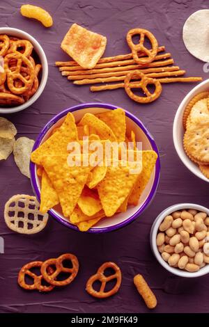 Croustilles tortillas et autres en-cas salés, plan d'eau à plat sur un fond vibrant. Assortiment de plats de fête Banque D'Images