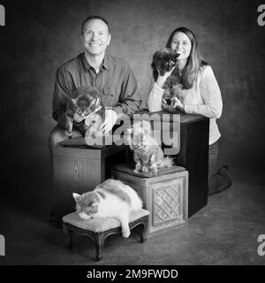 Studio portrait d'homme et de femme souriants avec quatre chats Banque D'Images