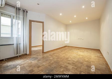 Chambre d'une maison vide avec parquet en chêne avec lattes disposées sous forme de chessboard, fenêtres avec rideaux et boiseries en chêne Banque D'Images