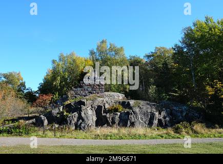 Vue sur la roche avec la partie du mur de pierre avec le tuyau sur elle avec les arbres de couleur automnale autour, Vallisaari, Helsinki Biennale 2021 Banque D'Images
