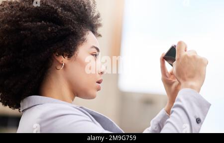 Ce bâtiment aura mon nom. une jeune femme d'affaires attirante debout seule sur le balcon à l'extérieur et prenant des photos avec son téléphone portable. Banque D'Images