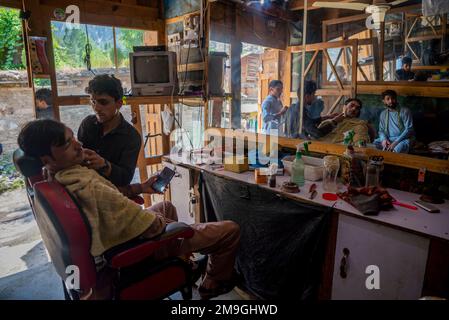 Client servi dans un salon de coiffure dans la région de Kalash, vallée de Bumburet, Pakistan Banque D'Images
