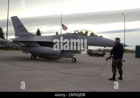 Pour reprendre la nuit, un CrewChief et un pilote de l'escadre 148th effectuent des vérifications opérationnelles de dernière minute d'un faucon de combat F-16 de la Garde nationale aérienne du Minnesota (Fighter Air Defense Fighter), avant un CAP de nuit (combat Air Patrol) attribué par NORAD. La FAA a demandé à la 148th Fighter Wing Wing de faire respecter l'interdiction de toutes les activités de combat commercial à la suite des attaques terroristes contre 11 septembre 2001 au Centre mondial du commerce et au Pentagone. Le drapeau repose à mi-mât en arrière-plan à la mémoire de ces vies perdues. Objet opération/série: BASE EAGLE NOBLE: Aéroport international de Duluth État: Minne Banque D'Images