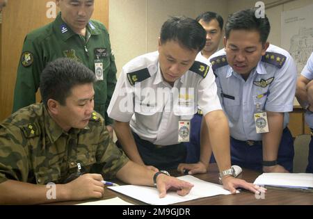 Le lieutenant-colonel J. Batsukh, (à gauche), officier des relations étrangères, Mongolie, explique son plan de déploiement du C-130 Hercules au major Francis Ngooi Choong Ngee, (au centre), Département des opérations aériennes, Singapour, et au capitaine Matyussof bin Matyassin, formation no 4 Escadron, Brunei, au RALLYE DE TRANSPORT AÉRIEN DU PACIFIQUE 2001. LE PACIFIC AIRLIFT RALLY (par) est un symposium militaire de transport aérien parrainé par le PACAF pour les pays de la région du pacifique. LE PAR est tenu tous les deux ans et est hébergé par une nation du pacifique. Cette année, la base aérienne d'Andersen, Guam est le pays hôte. Le symposium inclut des séminaires d'information avec la zone Banque D'Images