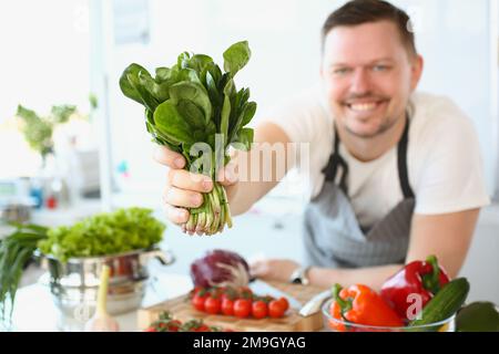 Un homme souriant fait cuire de l'ostrel ou de la salade dans la cuisine Banque D'Images