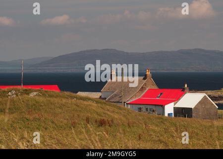 En regardant devant une maison au toit rouge jusqu'à White Strand de la plage de Monk, Iona et à Ulva et Mull au loin, Écosse Royaume-Uni Banque D'Images