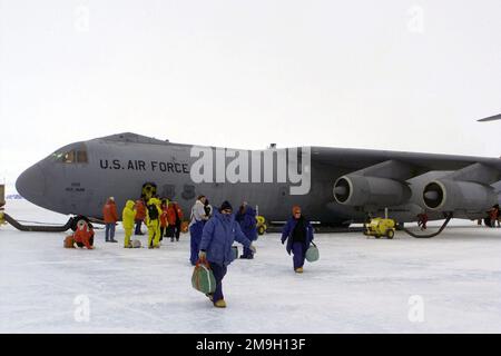 Un scientifique, des passagers et du personnel de soutien débarque d'un Starliger C-141C de Lockheed, de la 452nd Air Mobility Wing (AMW), de la base de réserve aérienne de mars, en Californie, stationné sur le bloc de glace à la station McMurdo à Ross Island, dans l'Antarctique, pendant l'opération DEEP FREEZE 2001. Le 452nd AMW exploite deux avions à partir de l'aéroport international de Christchurch, en Nouvelle-Zélande, pour soutenir le National Science Program des États-Unis sur LA GLACE. Notez les éléments chauffants fixés aux moteurs et aux freins de l'avion, pour les empêcher de geler dans le moins soixante-dix degrés froid. Sujet opération/série: DEEP FREEZE 2001 base: C Banque D'Images