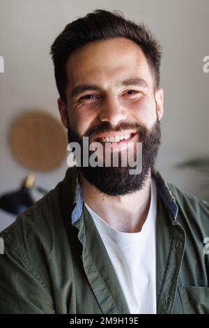 Gros plan portrait d'un jeune homme biracial barbu souriant contre un mur blanc, espace de copie Banque D'Images