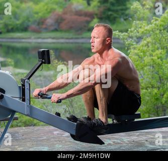 Homme s'exerçant sur une machine à ramer à l'extérieur, Bainbridge Island, Washington, États-Unis Banque D'Images