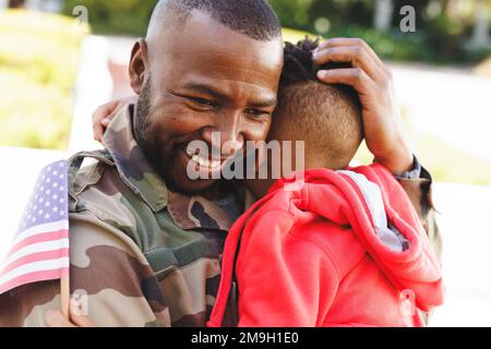 Heureux père afro-américain portant un uniforme militaire et son fils embrassant Banque D'Images