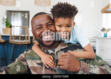 Portrait d'un heureux père afro-américain portant un uniforme militaire et son fils embrassant Banque D'Images