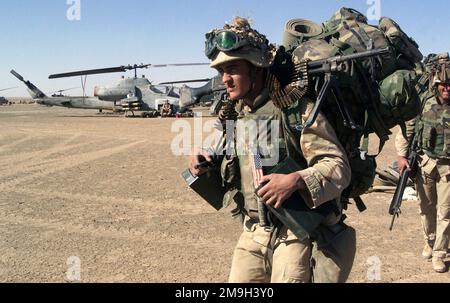 Près d'un hélicoptère d'attaque AH-1W Super Cobra du corps des Marines (USMC), un fantassin doté de l'unité expéditionnaire maritime 15th (MEU), capable d'opérations spéciales (SOC), porte une charge de combat complète, y compris un canon de machine FNMI 7,62 mm M240, Tout en se déplaçant en position de sécurité après avoir saisi une base opérationnelle avant pour soutenir l'opération ENDURING FREEDOM. Sujet opération/série: LIBERTÉ DURABLE pays: Afghanistan (AFG) Banque D'Images