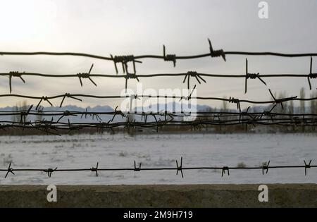 Une chaîne de montagnes près de l'aéroport international de Manas, Bichkek, Kirghizistan, à travers une clôture en barbelés. Objet opération/série: BASE DE LIBERTÉ DURABLE: Aéroport international de Manas pays: Kirghizistan (KGZ) Banque D'Images