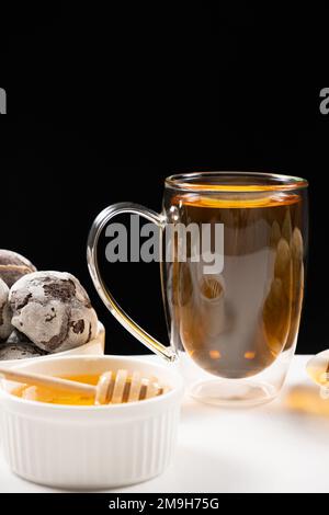 Une tasse de thé noir fort, une grande tasse en verre avec un double fond sur fond noir. Banque D'Images