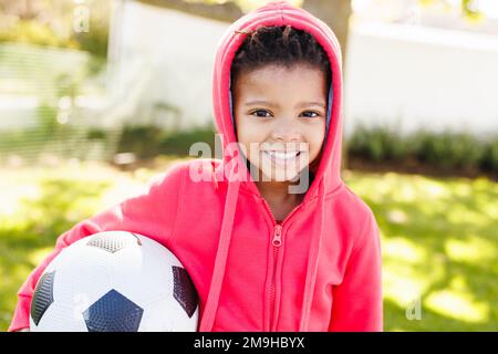 Portrait d'un garçon afro-américain heureux tenant le football dans l'arrière-cour Banque D'Images