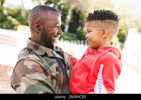 Heureux père afro-américain portant un uniforme militaire et son fils embrassant Banque D'Images