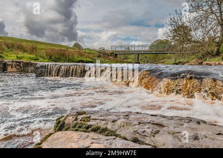 Cascade et passerelle au-dessus de Sleightholme Beck, East MellWaters, Bowes. Le sentier longue distance Pennine Way passe à proximité. Banque D'Images