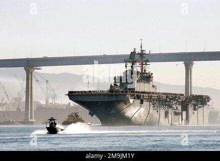 Vue de l'avant-port de la marine américaine (USN) CLASSE WASP : NAVIRE D'ASSAUT AMPHIBIE, USS BONJOMME RICHARD (LHD 6), passant sous le pont Coronado, en cours dans le port de San Diego, Californie (CA), le personnel des navires devant les rails au départ pour un déploiement prévu de six mois. Une patrouille portuaire de l'unité de sécurité portuaire est en cours au premier plan. Base: San Diego État: Californie (CA) pays: Etats-Unis d'Amérique (USA) Banque D'Images