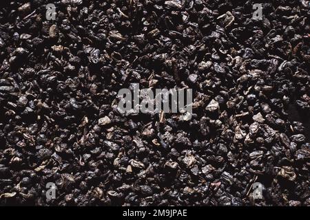 Fond de texture de thé noir. Feuilles de thé séchées noires, marco. Motif de feuilles de thé noir sur une surface plane. Banque D'Images