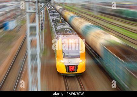 Le train électrique jaune de banlieue avec des voitures particulières se précipite le long de la voie ferrée, vue aérienne Banque D'Images
