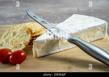 Le fromage français Brie sert des tomates prune ed et de minces craquelins sur un plateau en bambou Banque D'Images