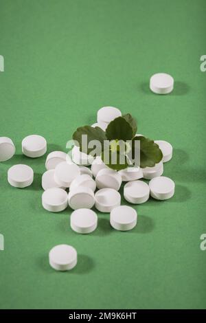 Pilules blanches de fines herbes et de vitamine nourriture saine librement posée sur fond vert Banque D'Images