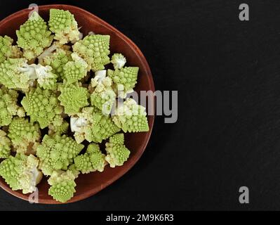 vue de dessus des fleurs romanesco fraîches dans un bol en bois sur une plaque en ardoise noire avec espace pour copier Banque D'Images