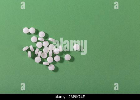 Pilules blanches de fines herbes et de vitamine nourriture saine librement posée sur fond vert Banque D'Images