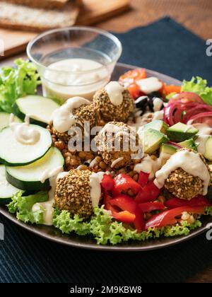 Salade mixte saine pour le dîner avec des boulettes de falafel faites maison et une vinaigrette de tahini. Banque D'Images